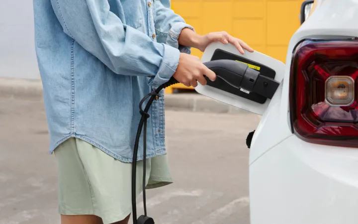 Pessoa conectando um carregador a um carro elétrico
